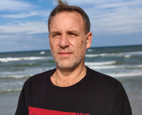 Primo piano di Roberto Quintavalle, sullo sfondo il mare di Rimini