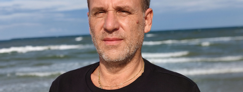 Primo piano di Roberto Quintavalle, sullo sfondo il mare di Rimini